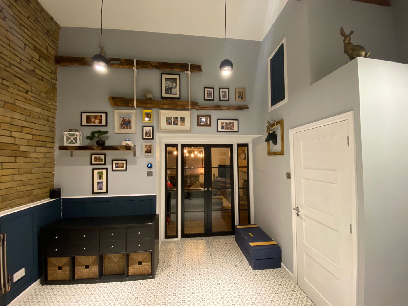 Hallway with exposed brick, navy panelling and Crittall doors